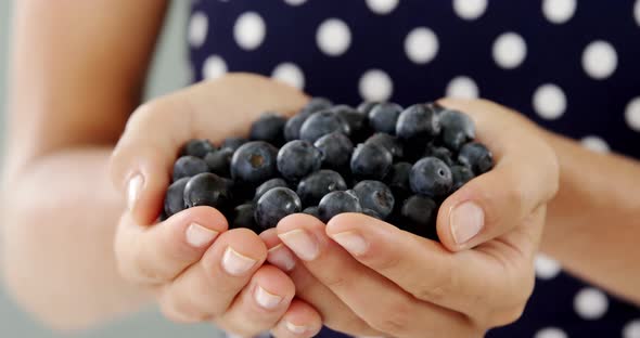 Close-up of woman holding blueberry alt