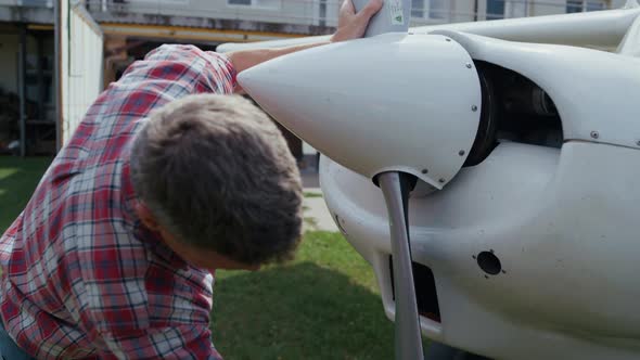 Airplane Engineer Checking Propeller Blades After Landing on Aerodrome Close Up alt