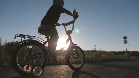 Little Boy Learning To Ride on Bicycle on Sunset Time. alt