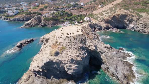 Drone flies over the rocky nature and blue sea with swimmers and boat in sight alt