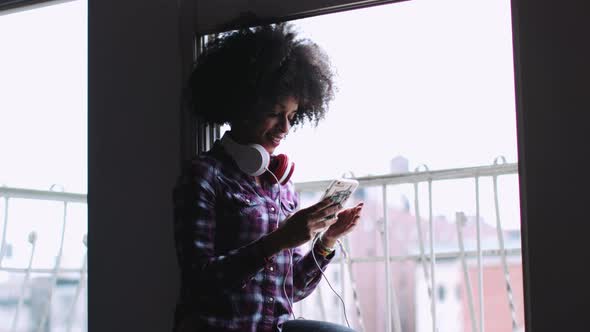 Afro American Female with smart phone, wearing headphones