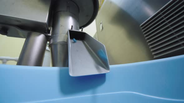 Closeup of Blue Capsules Falling Down to the Container From Automated Pharmaceutical Machinery