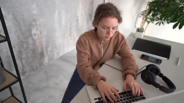Serious Teen Girl Working with Laptop in Coworking Space alt