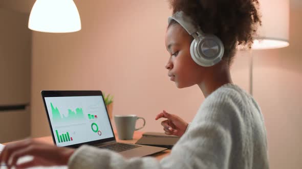 Young African Girl is Learning to Work with Financial Statistics on a Remote Work at Home Working alt