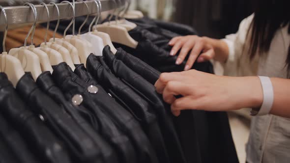 Women's Hands Choose a Leather Jacket in a Clothing Store Closeup