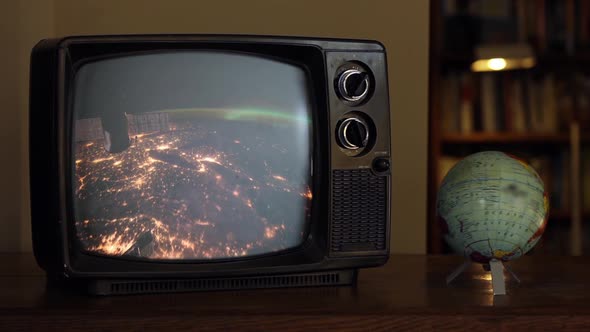 Earth from Space Seen on a Retro TV near a Globe Map. Zoom In. alt