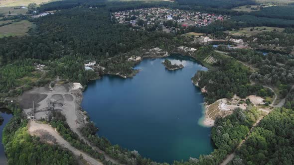 Aerial View of lake with Beautiful Water in a Quarry Surrounded by Forest, Small Town and Mining Ope alt