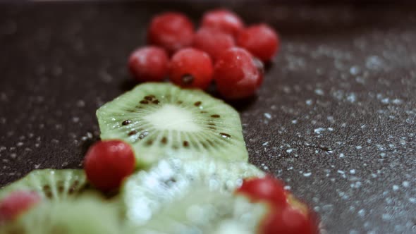 Juicy Fresh Kiwi Slices and Frozen Red Currant Arranged in a Shape of Christmas Tree on a Black alt