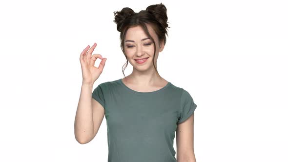 Portrait of Young Woman with Double Buns Hairstyle Smiling on Camera and Gesturing Altight Symbol alt