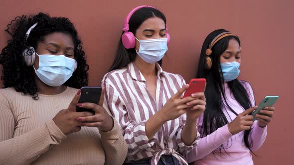 Multiracial women using mobile smartphone and listening music with wireless headphones alt