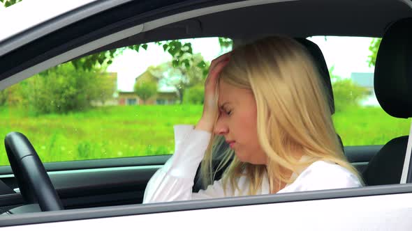 Young Attractive Blond Woman Sits in the Car and Has Depression alt