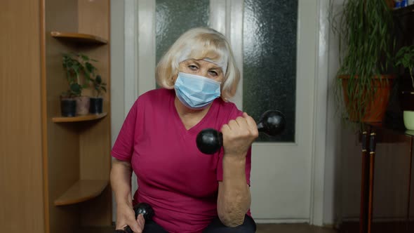 Elderly Senior Grandmother Making Weight Lifting Dumbbells Exercising During Coronavirus Lockdown alt