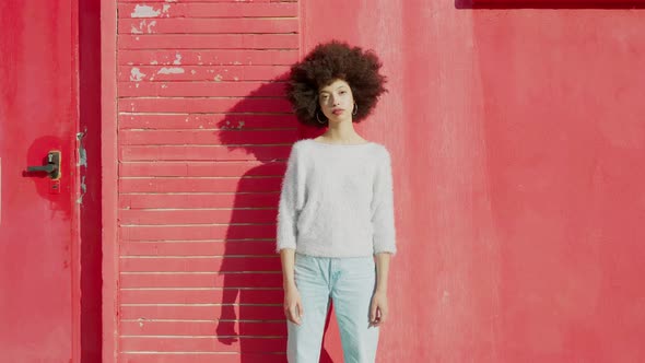 Young sad woman standing in front of red wall alt