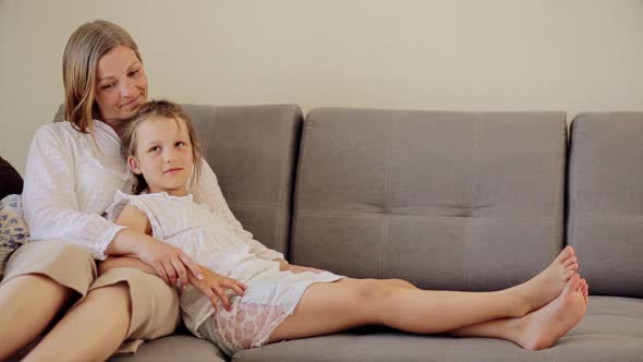 Smiling Mature Woman Embracing Daughter at Couch
