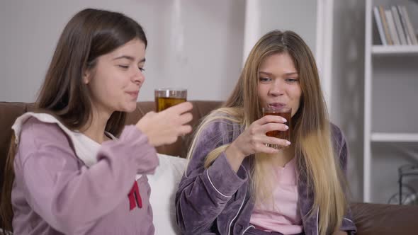 Two Young Women Toasting Drinking Juice at Pajama Party Smiling Talking alt
