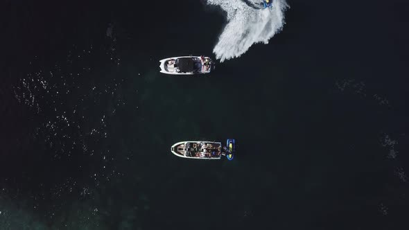 Top view of two standing motor boats and water scooter around them on emerald beach in Black sea 4k