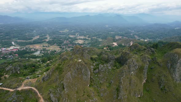 Green mountain cliffs overlooking a city in the valley of Tana Toraja in Sulawesi Indonesia. alt