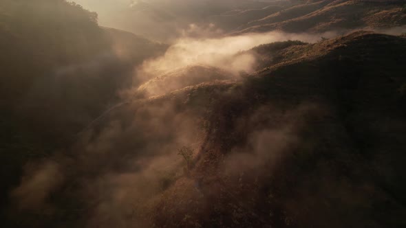 4K Aerial view from drone over mountains fog. Golden scenery at sunrise alt
