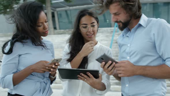 Three Business People Standing Outside with Smartphones and Tablet Computer alt