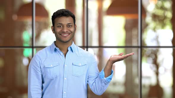 Young Smiling Brownskinned Man Rising Palms Up Showing Copyspace alt