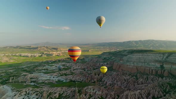 Hot air balloons fly over the mountainous landscape of Cappadocia, Turkey. alt