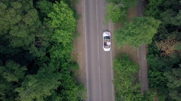 Vertical Aerial View Wedding Couple Sits in Convertible alt