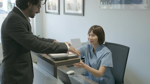 Dental assistant speaking with patient at front desk alt