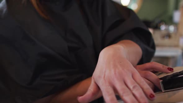 Female customer wearing face mask choosing from hair color sample chart at hair salon alt