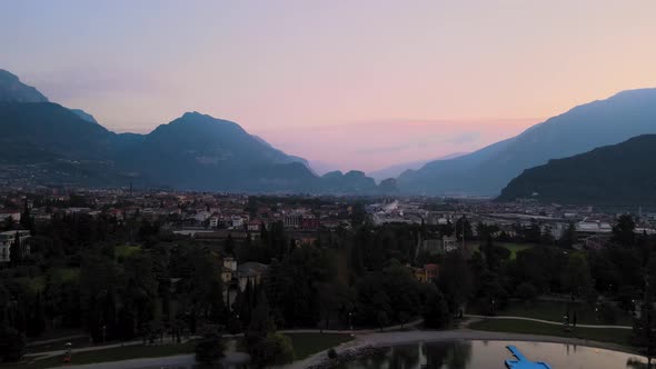 Aerial view of Riva del Garda at sunrise. City overview with mountains and pink sky. Shooting in 4k alt