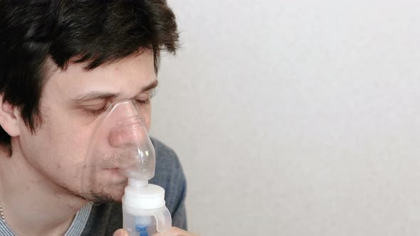 Use Nebulizer and Inhaler for the Treatment. Young Man Inhaling Through Inhaler Mask