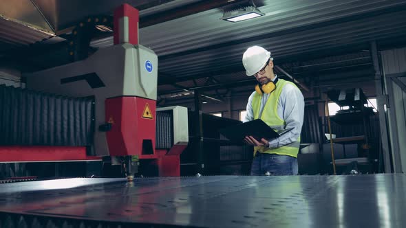Male Worker Is Observing a Laser-cutter Processing Metal alt