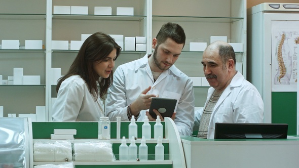 Smiling team of pharmacists two male and one female, stand