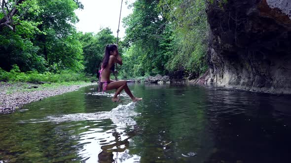 Cute Smiling Asian Girl in Bikini Having Fun on a Rope in the River Thailand