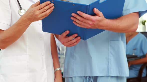 Two doctors holding clipboard in medical office alt