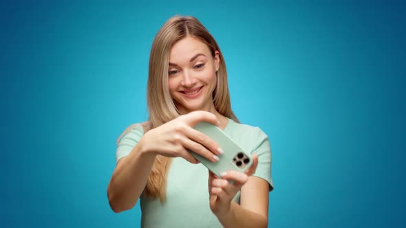 Young Woman Playing Games on Her Smartphone in Studio alt