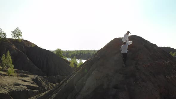 Man in Gray Sweater Helps Beautiful Slender Woman in White Long Wedding Dress to Go Down the alt