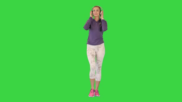 Young Athletic Girl on a Walk with Headphones on a Green Screen Chroma Key alt