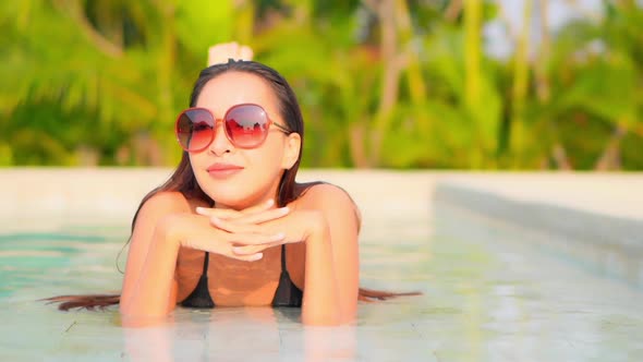 Young asian woman enjoy around outdoor swimming pool for leisure alt