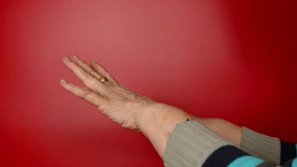 Elderly Woman's Hands on Red Background alt