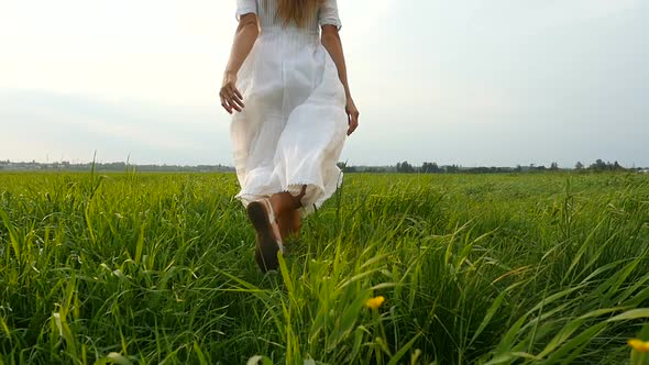 Back view of Beautiful woman running on the green grass. Wind blowing hair. 