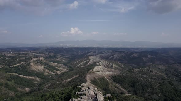 -PLANE: from crane back to bird's eye view-DESCRIPTION: video with drone over the civita di Bagnore alt