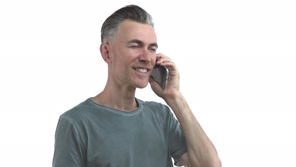 Handsome Middleaged Slim Guy with Bristle and Grey Hair Talking on Mobile Phone Smiling and Nodding alt