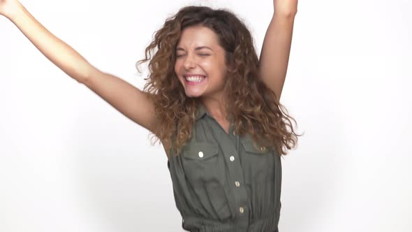 Young Energetic Curly Woman Suddenly Appearing on Camera Dancing Smiling Happily Isolated on White alt