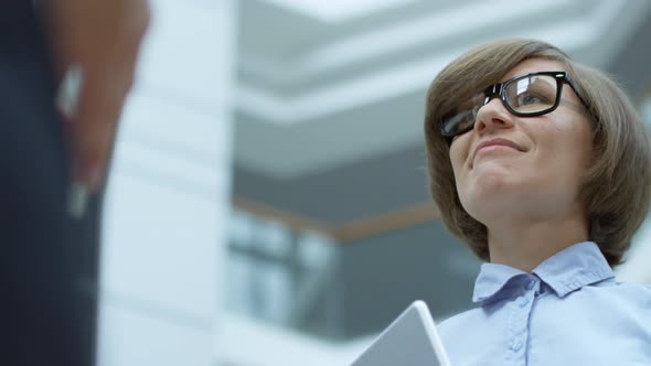 Businesswoman Holding Tablet and Speaking with Colleagues alt