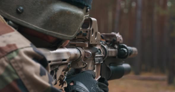 A Soldier in a Special Military Uniform with a Helmet on His Head and with a Sniper Rifle in the alt