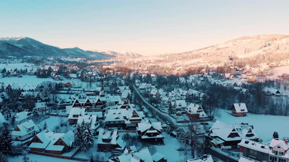 Snow Covered Town In The Daylight With Clear Blue Sky  Vehicles On The Street alt