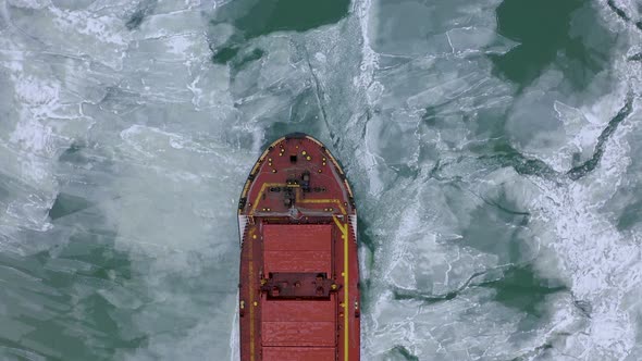 Aerial Above Epic Huge Steel Ship Breaks Ice By Bow of Ship and Floats in Large Sea Ice Floes alt