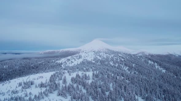 Drone Rising Above Hills Revealing Big Summit Covered in Snow