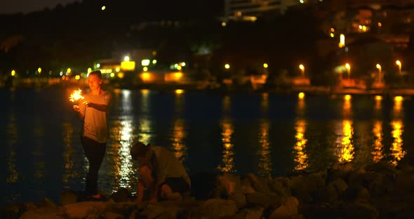 Couple Holding Sparklers at Seashore alt