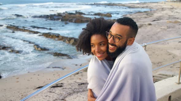Couple in blanket kissing each other at beach 4k alt